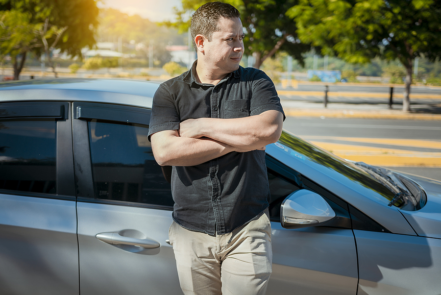 Man standing in front of his car with his arms crossed looking confident